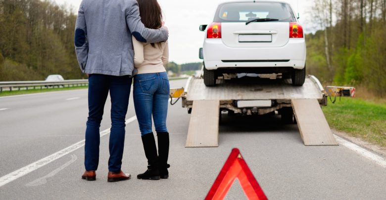 Couple near tow-truck picking up broken car