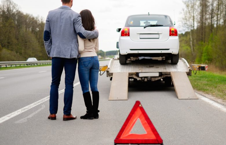 Couple near tow-truck picking up broken car