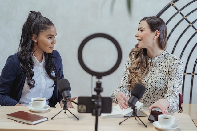 smiling-woman-interviewing-black-female-guest-and-recording-video